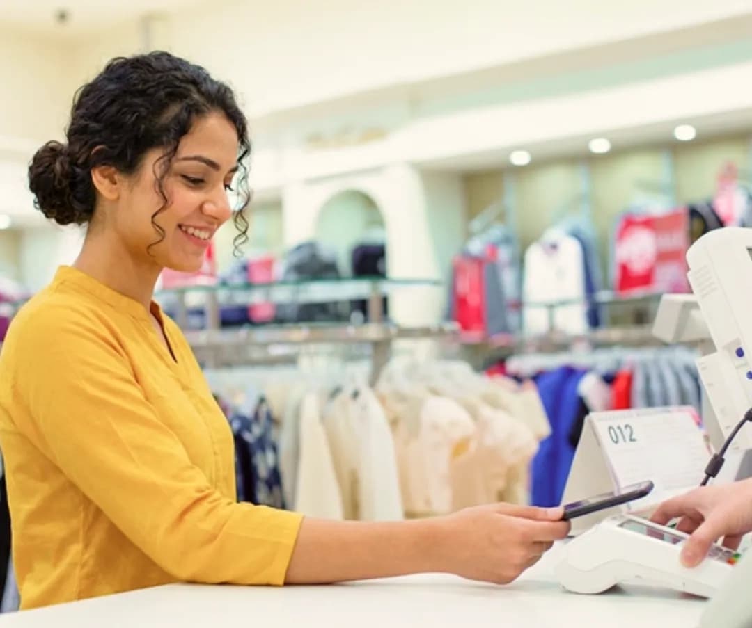 Smiling cashier serving a customer at a fashion store checkout