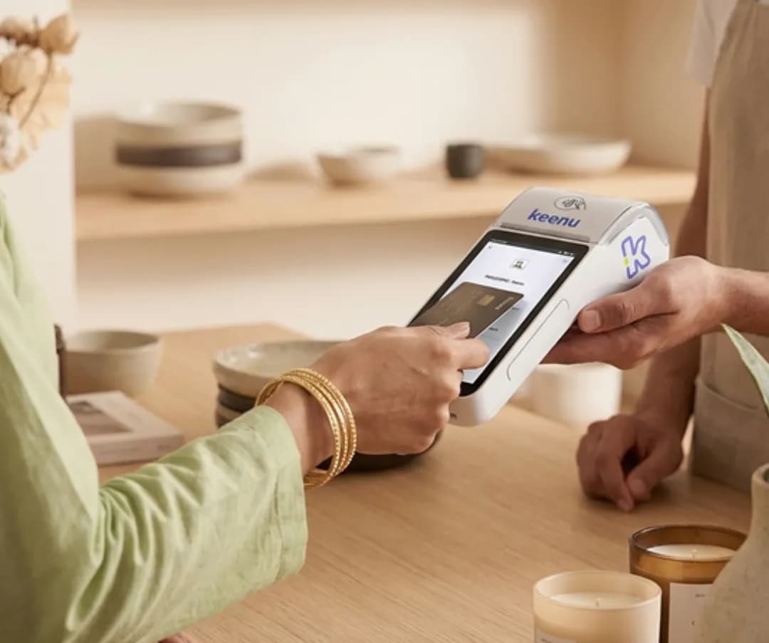 Shop worker using a Keenu device to track sales while serving a customer