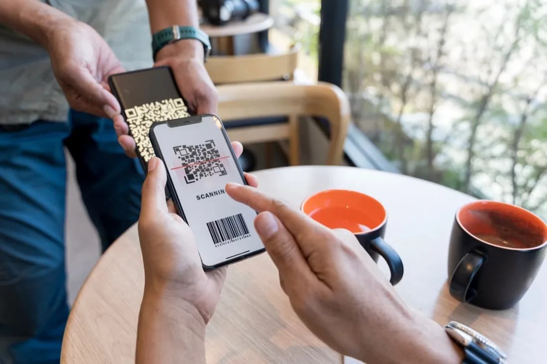 Customer scanning a Keenu QR code with a smartphone at a counter